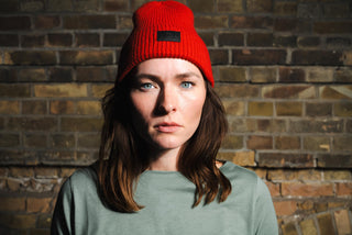 Julia trägt die rote Beanie und unser elegantes 'Cheers' T-Shirt – der perfekte Look für gemütliche Wintermomente bei Winecraft.