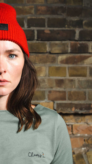 Julia trägt die rote Beanie und unser elegantes 'Cheers' T-Shirt – der perfekte Look für gemütliche Wintermomente bei Winecraft.