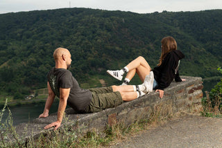 Mann und Frau sitzen auf der Weinbergsmauer und tragen ein T-Shirt und Hoodie von Winecraft.